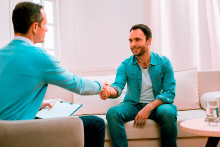 Happy glad man shaking hands with psychologist