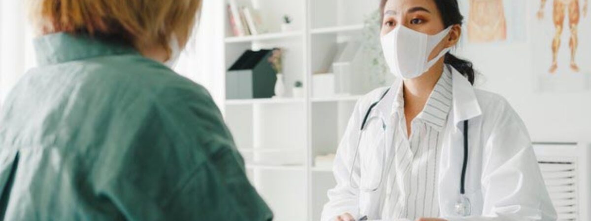 young-asian-lady-doctor-wearing-protective-mask-using-clipboard-discussing-results-symptoms-with-girl-patient-hospital-office_7861-2839